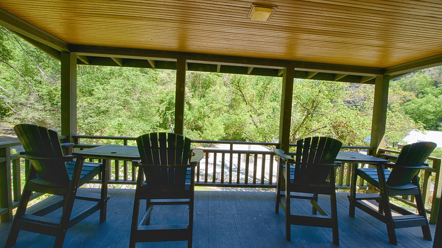 a porch featuring four chairs overlooking towards the lush green wildernessfull view image of a bedroom with wooden interiors featuring two beds - Historic Tapoco Lodge