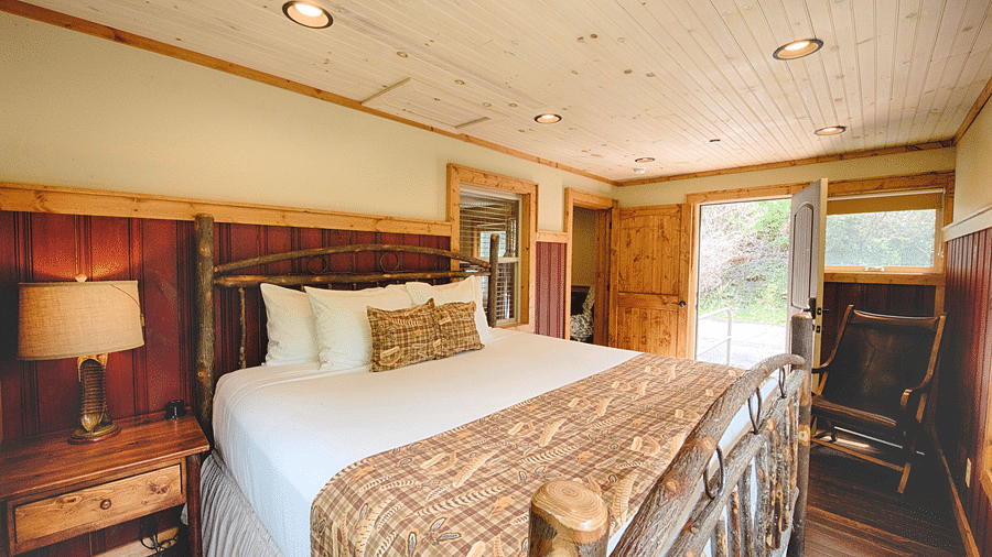 close up image of a plush double bed with a door opening to the exterior of the room - Historic Tapoco Lodge