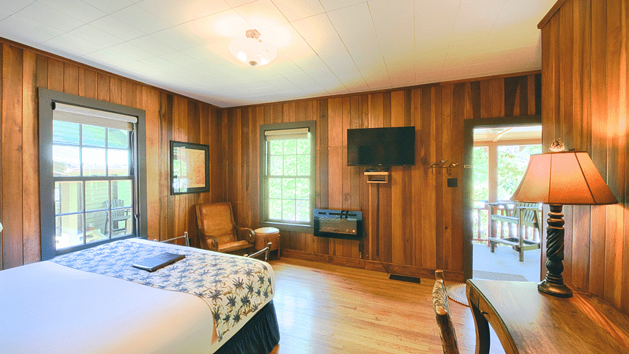 a spacious room adorned with wooden walls, a double bed and a wall mounted flat screen television - Historic Tapoco Lodge