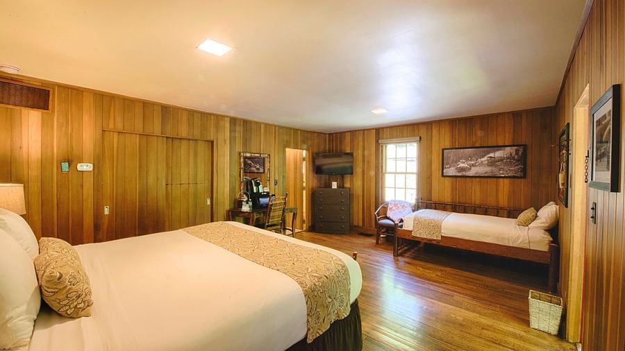 corner view image of a room wooden walls and flooring featuring two plush comfortable beds - Historic Tapoco Lodge