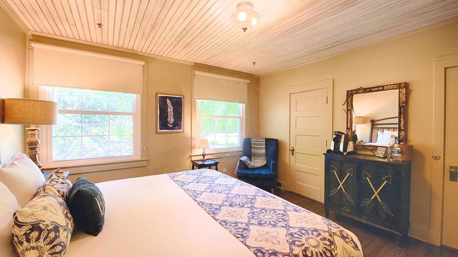 full view image of a cozy bedroom with a comfortable double bed and a wooden cabinet along with a mirror above it - Historic Tapoco Lodge