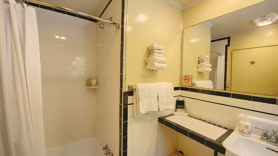 a close up image of a bathroom with a bathtub and a wash basin along with a wide mirror and fresh towels hanging on the side - Historic Tapoco Lodge