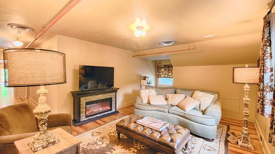 full view image of the living area with a soft couch adorned with a lot of cushions and a beautiful center piece - Historic Tapoco Lodge