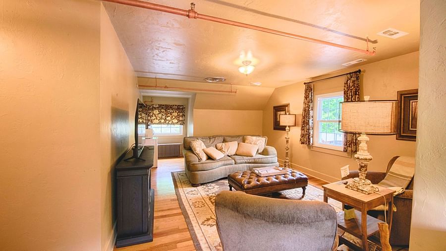 a spacious living room featuring a plush couch and two arm chairs in front of it - Historic Tapoco Lodge
