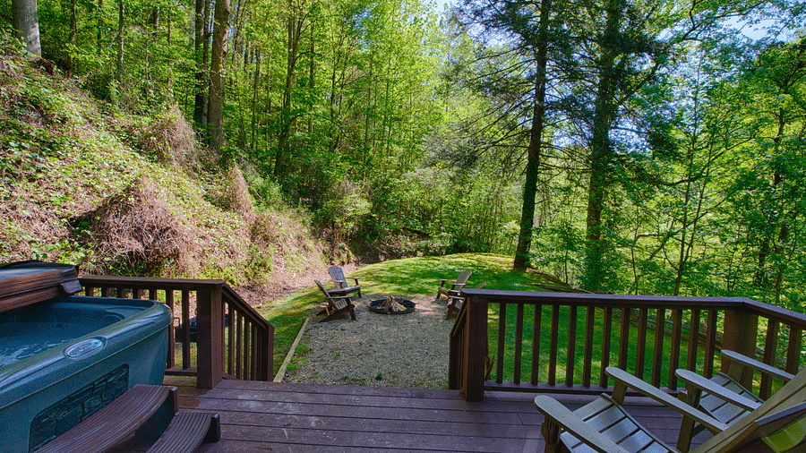 a wooden porch with an outdoor seating area and a Jacuzzi tub overlooking the beautiful greenery - Historic Tapoco Lodge