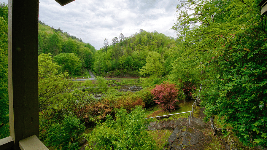 a beautiful lush green scenery from the wooden porch with a cloudy sky in the background - Historic Tapoco Lodge