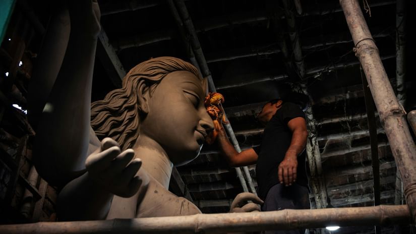 Artisan sculpting a clay idol in a workshop.