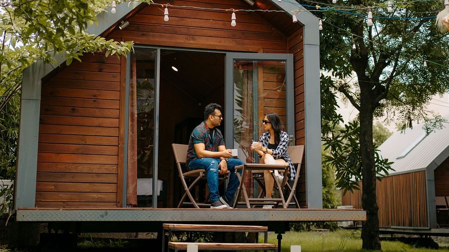 A couple sits outside the cottage room, chatting and enjoying the surrounding natural view at Crescent Spa & Resort, Indore