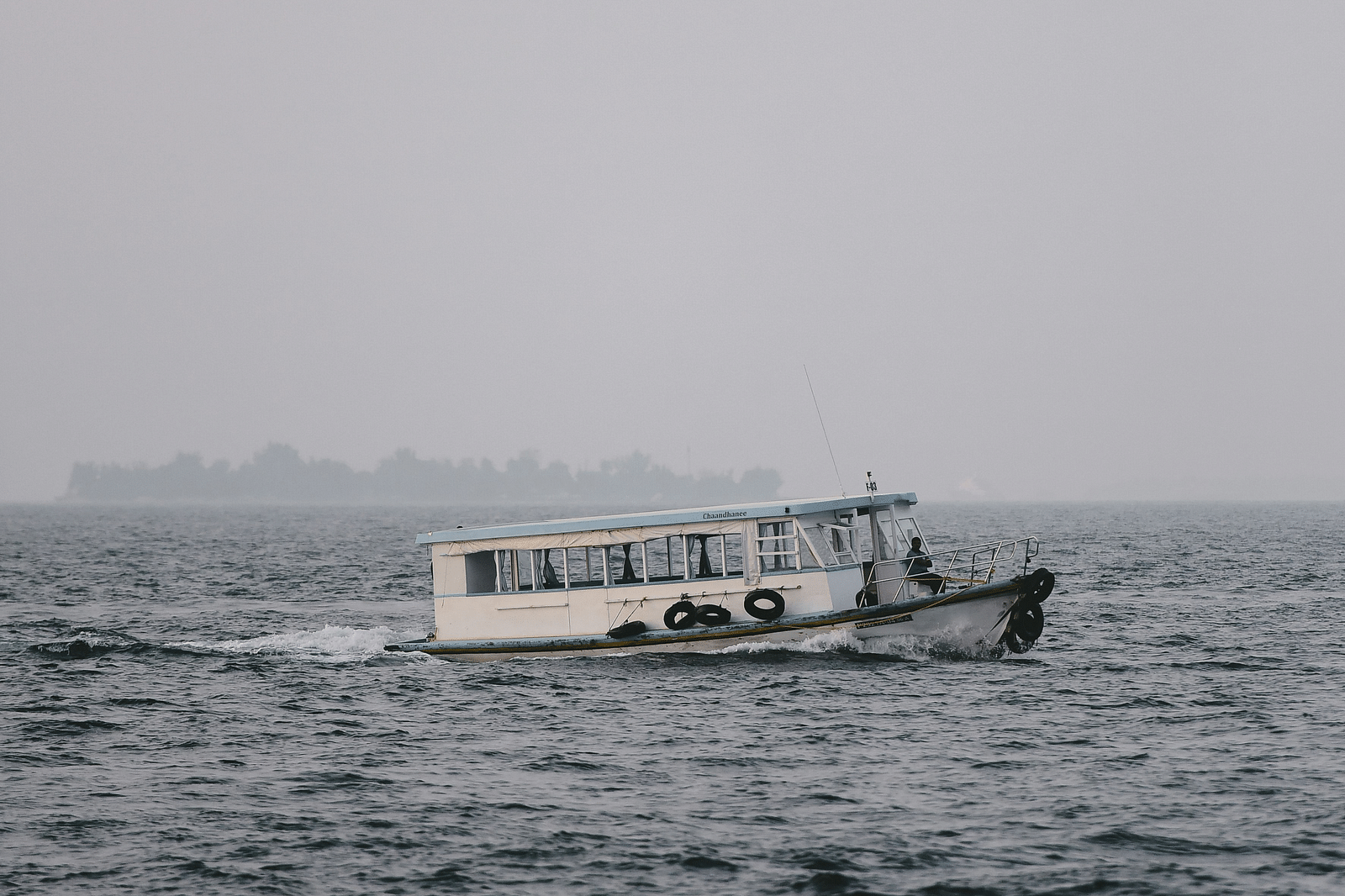 A solitary ferry travelling on a waterbody in the evening sky