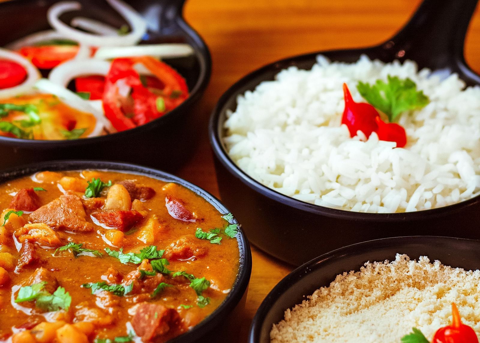 close up image of black coloured bowls with steamed rice, a side dish and some salad