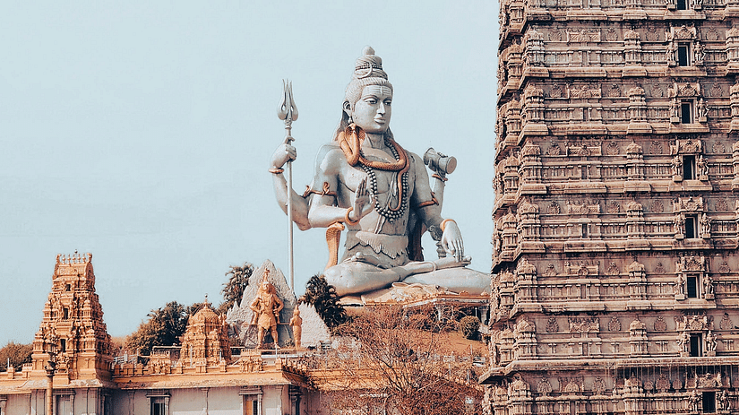 View of a statue of Lord Shiva with a temple gopuram in the foreground