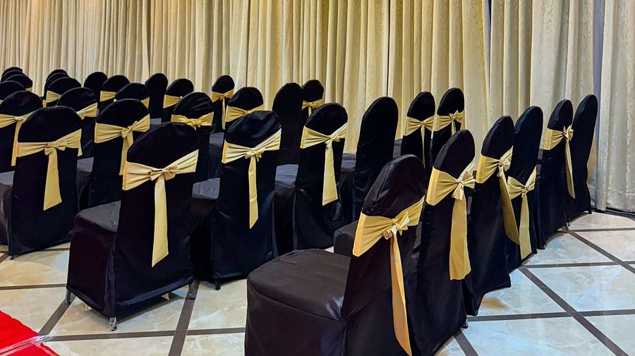 Chairs with black covers and gold sashes are arranged in an hall at Silver Sand Sea Princess Beach Resort, Port Blair.