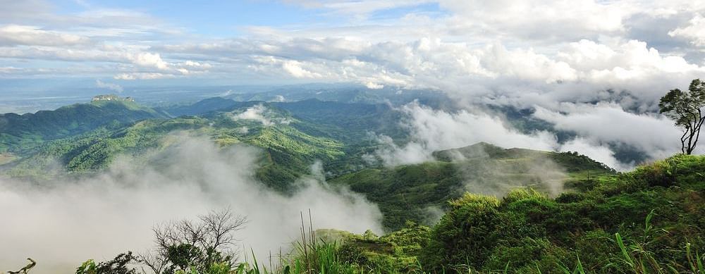 A view of a mountain range covered in mist, with a clear blue sky in the background.