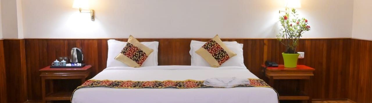 An image of a room featuring a bed, bed side table, wall hangings and rug - Ecotel Chiminda, Pelling