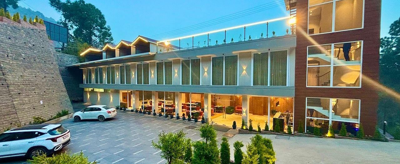 Exterior view of the ARNISA Boutique Hotel building with glass facade and neatly landscaped driveway