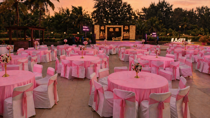 Outdoor lawn event venue decorated with pink tablecloths and draped seating at Kenilworth Resort & Spa, Goa.