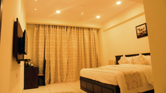 A side view of a bedroom shows the off-white interiors and the TV on the wall - VITS ExcellenSea, Dapoli