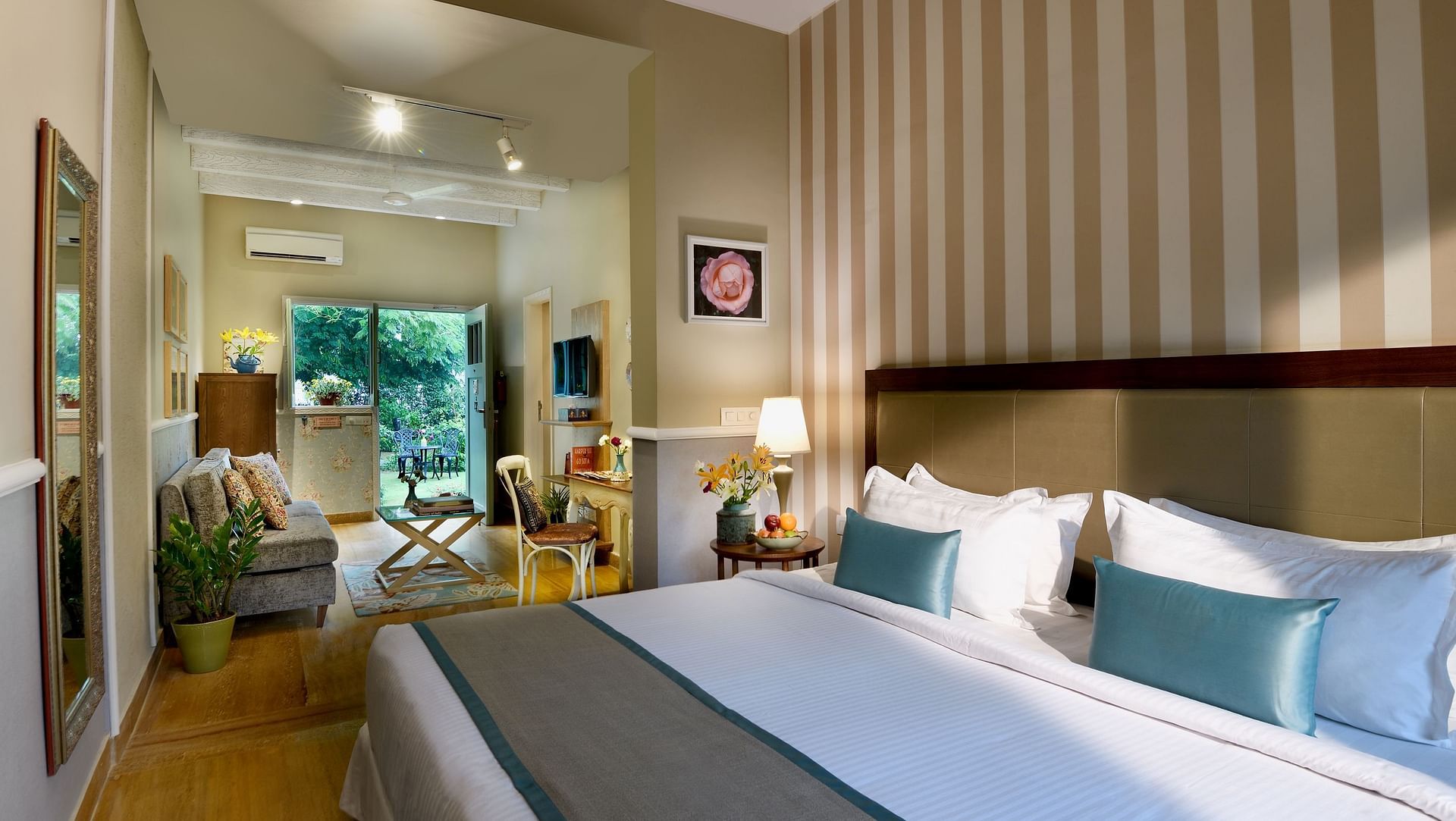 A double bed with white linens, blue runner, striped wall panel, and desk in a room at Karma Chalets.