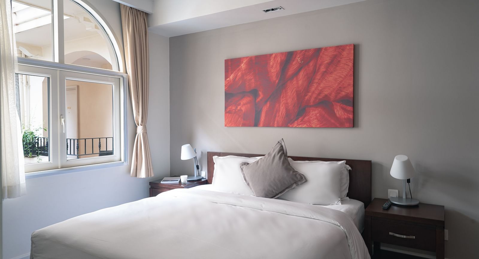A bedroom with a large bed, a nightstand, and a piece of art on the wall | Two-bedroom Suite | Central Mansions, Phnom Penh