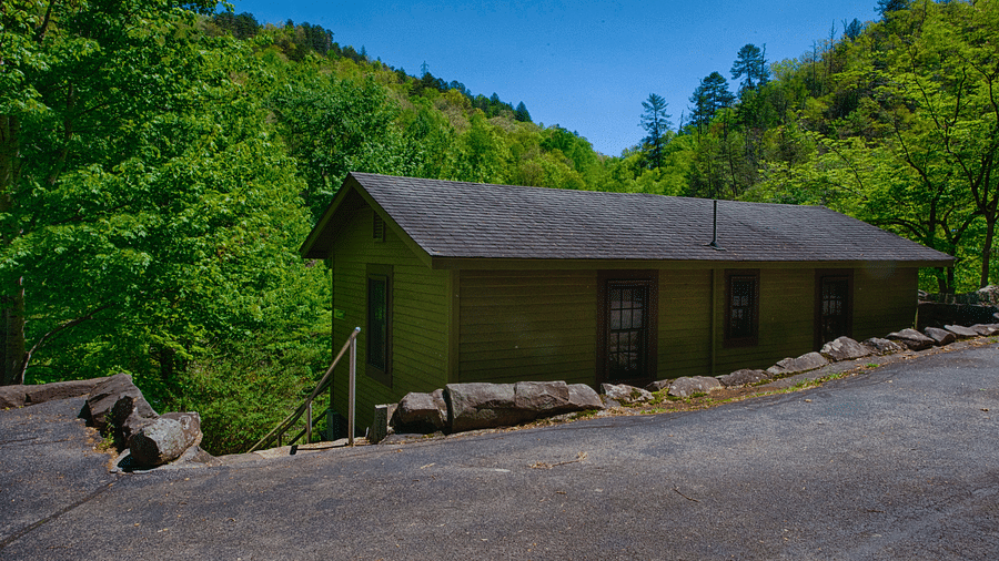 the Overlook cabin with green exterior walls and dark grey room with lush green hills in the background - Historic Tapoco Lodge