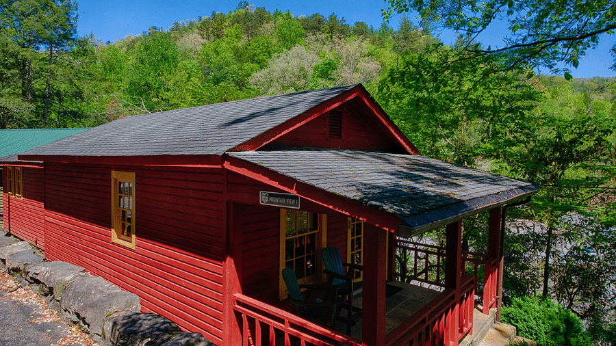 a bright facade image of a cabin win bright red colored exterior with lush green mountains in the background - Historic Tapoco Lodge