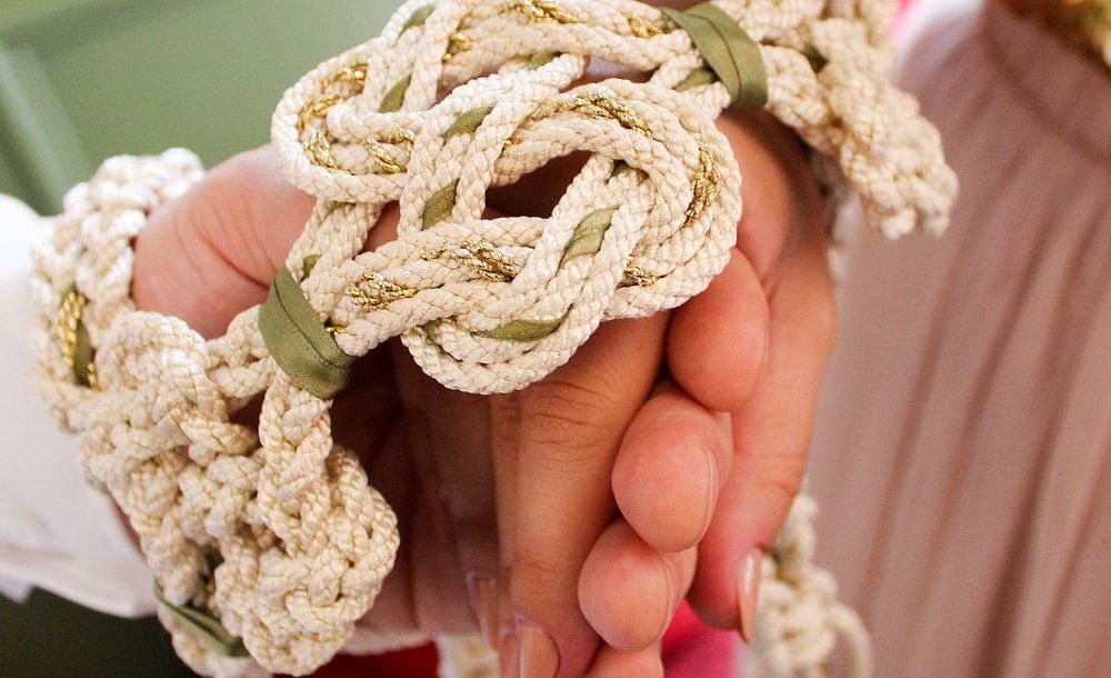 Close-up of hands with entwined ropes symbolizing unity