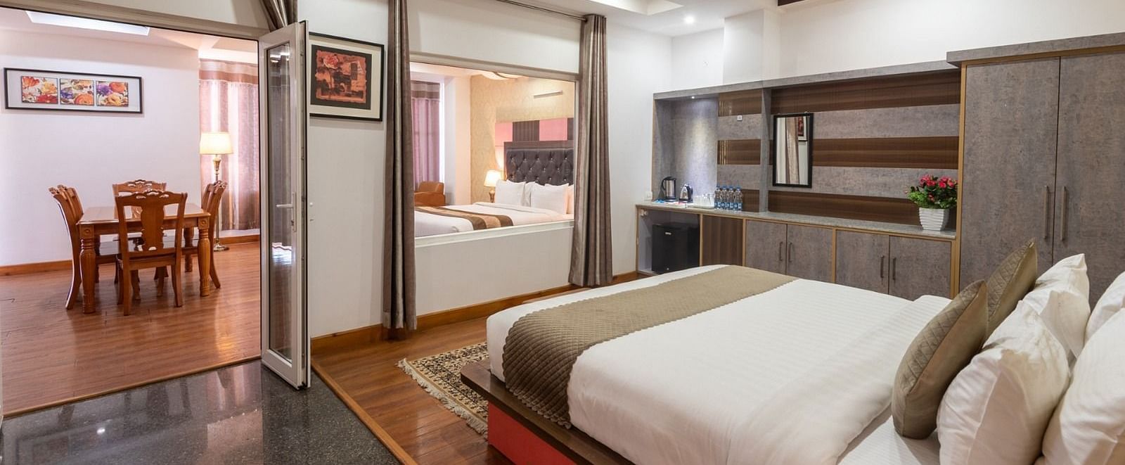 Extended view of the Family Suite furnished with a King and Queen size bed, dining table for four, and wardrobe at DLS Hotel Shiva Sanctuary & Spa in Dharamshala.