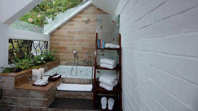 Modern bathroom with skylight over spa bath and shelved towels.