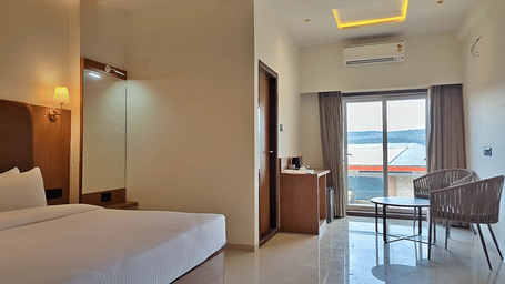 Bedroom with a double bed, seating area, and glass doors opening to a balcony.
