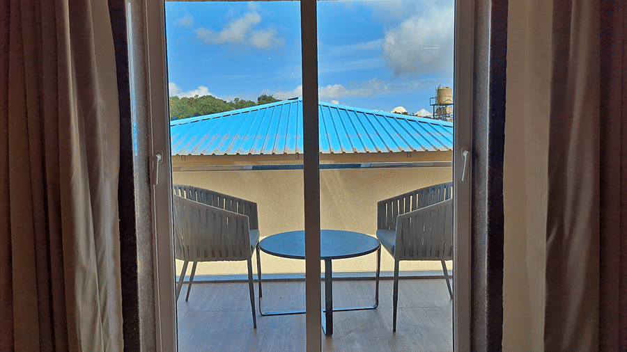 Balcony with two chairs and a round table overlooking surrounding scenery.