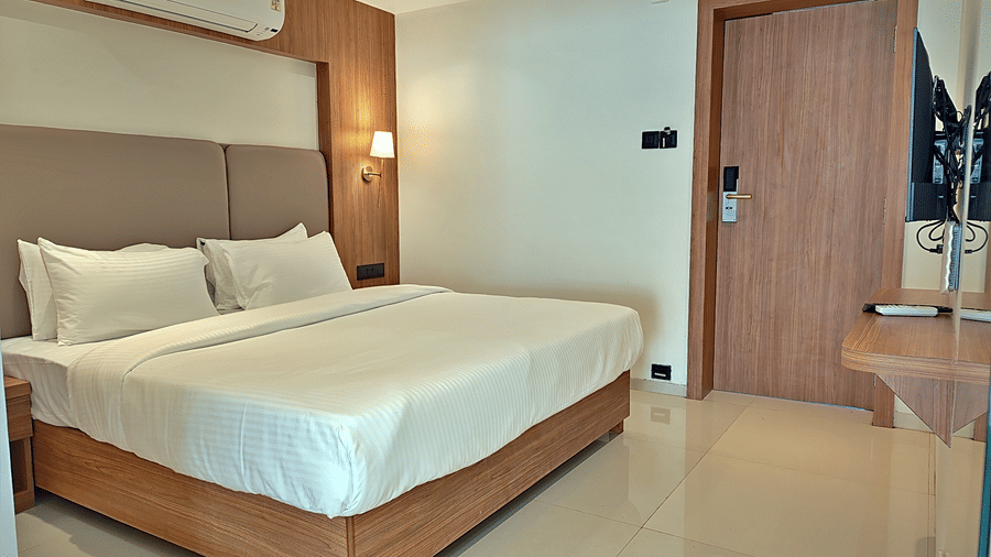 Bedroom with a double bed, padded headboard, bedside lights, and air conditioner.
