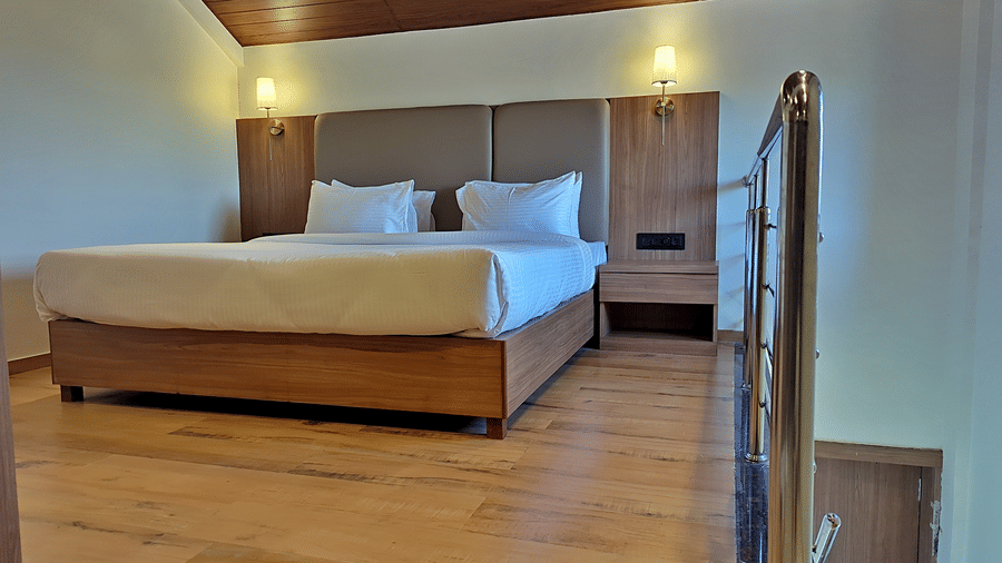 Bedroom with a double bed, wooden staircase, and glass railing.
