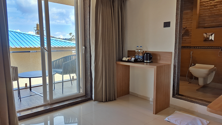 Room with a double bed, balcony access, wooden furnishings, and an adjoining bathroom.