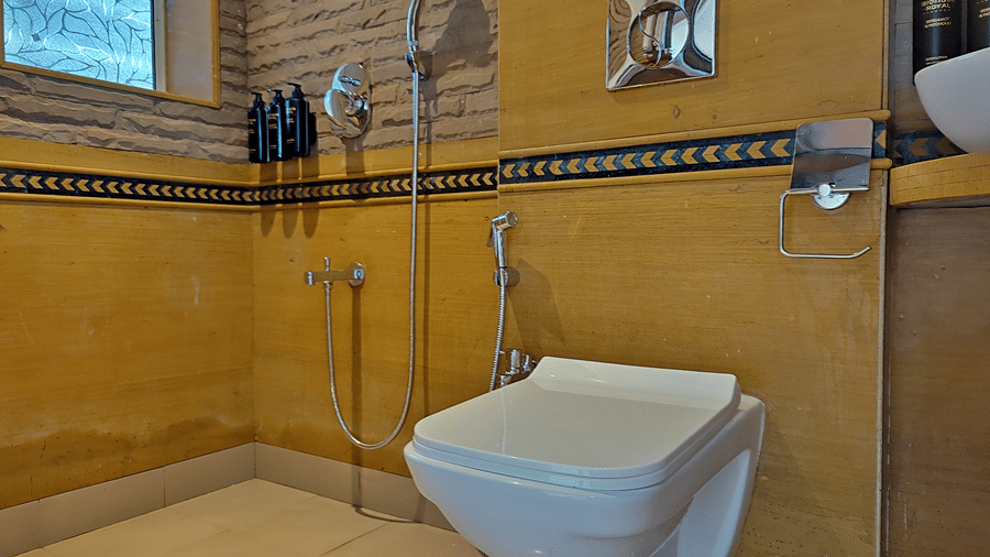Bathroom with a toilet, shower area, fixtures, and tiled walls.
