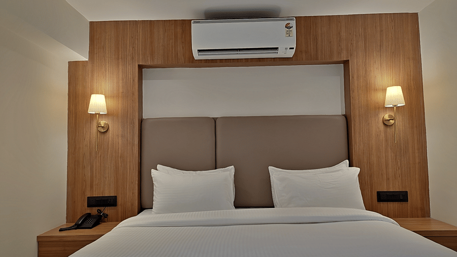 Bedroom with a double bed, wooden headboard, bedside lights, and air conditioner