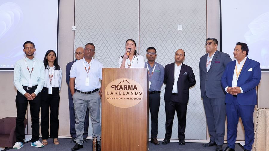 Speaker addressing an audience with a microphone and a few people on the stage - Karma Lakelands.