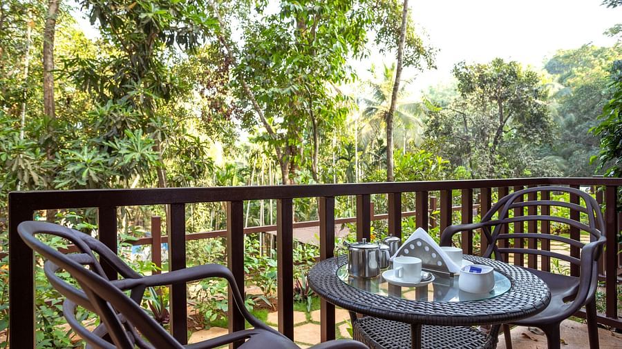 A balcony with the view of lush green trees in one of our cottage - Stone Wood Nature Resort, Gokarna