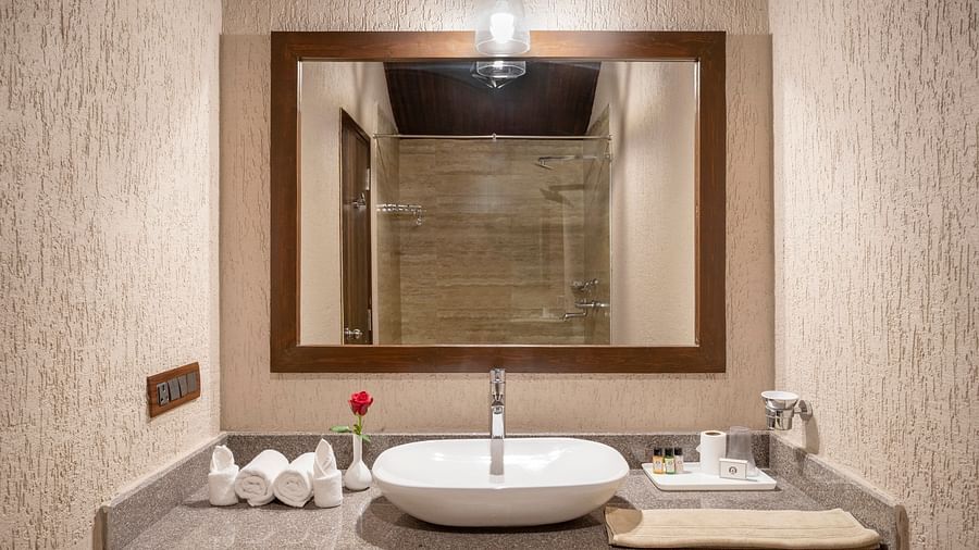 A bathroom with a large sink, neatly folded laundry by the side and a mirror - Stone Wood Nature Resort, Gokarna