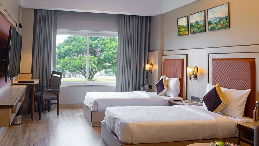 Elegant twin bedroom with large windows & work space at The Lalita Grand hotel 