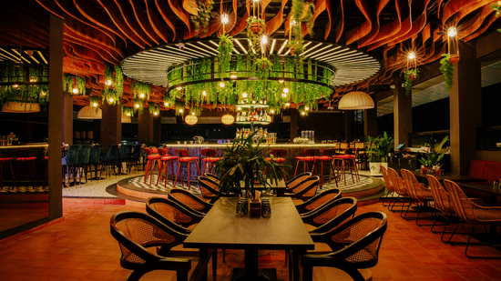 Elegant dining space with a central bar adorned with greenery and warm lighting. |  The Icon Select by Bhagini, Mahadevapura