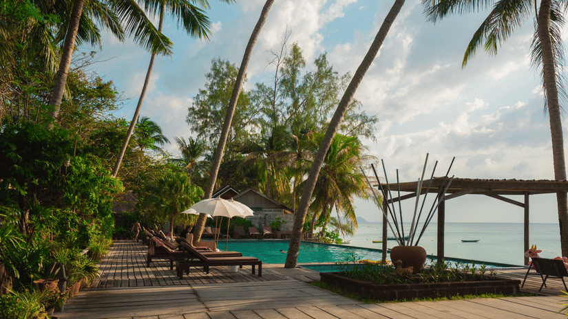 wooden deck with a swimming pool and the sea in the background