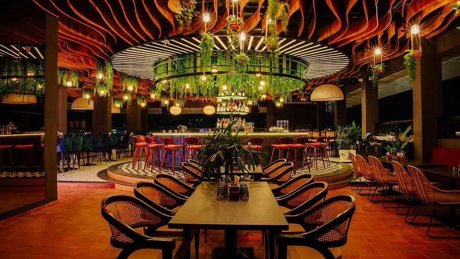 Elegant dining space with a central bar adorned with greenery and warm lighting. |  The Icon Select by Bhagini, Mahadevapura