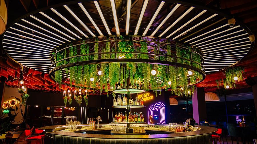 Stylish bar area with hanging greenery and vibrant lighting in a modern restaurant. | The Icon Select by Bhagini, Mahadevapura