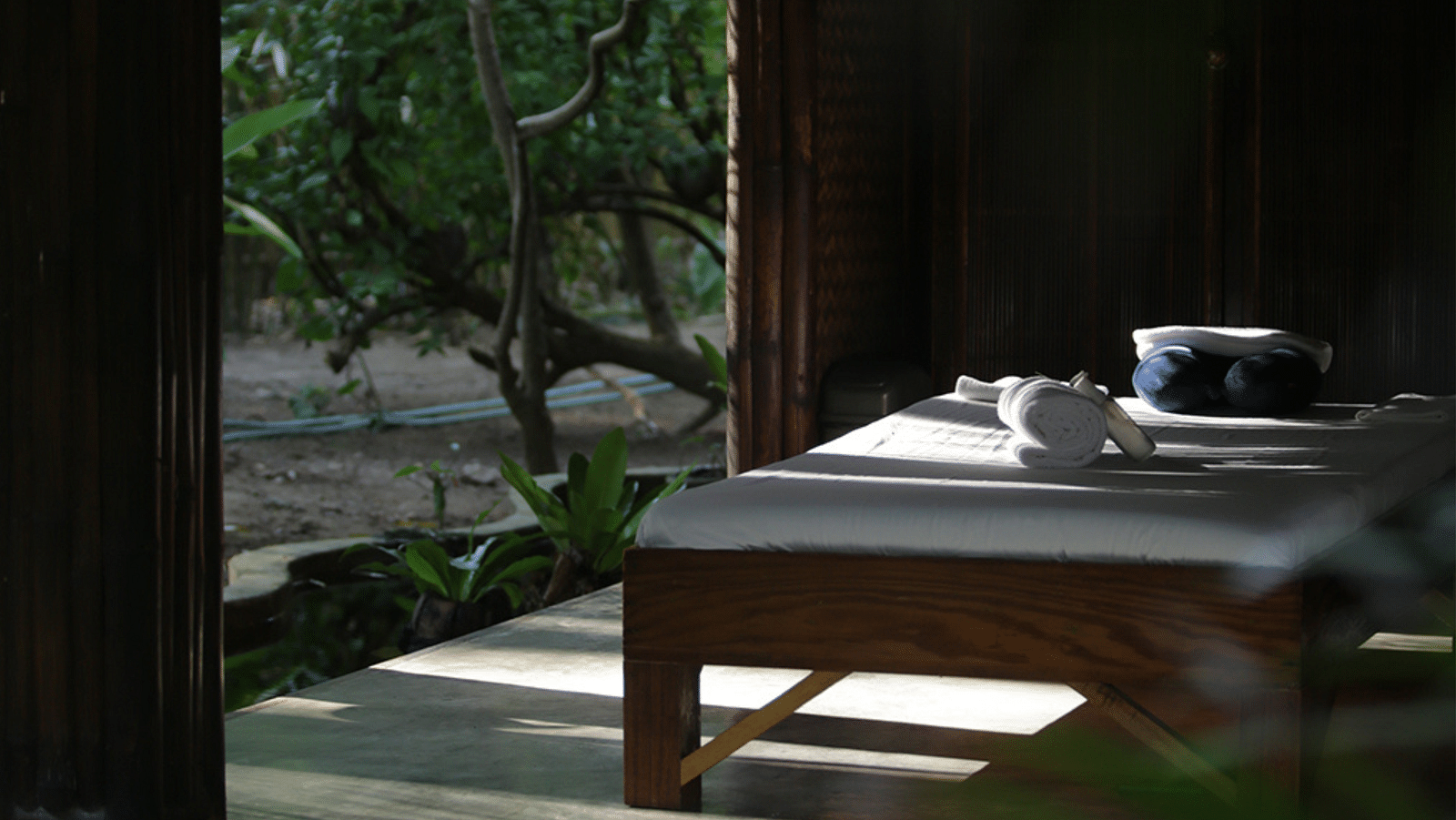 Massage table set outdoors facing the beach under the shade at Flower Island Resort.