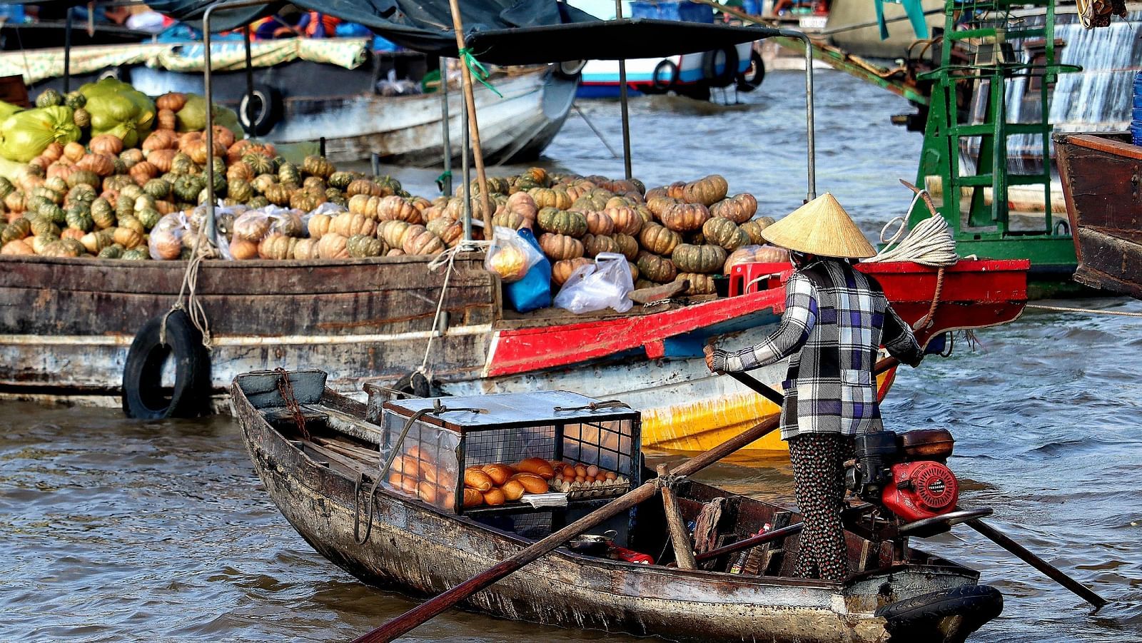An overview of a floating market in the Mekong River with people on boats selling many items.