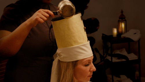 Liquid being poured onto a conical cap on the head of a person at YO1 Longevity & Health Resorts
