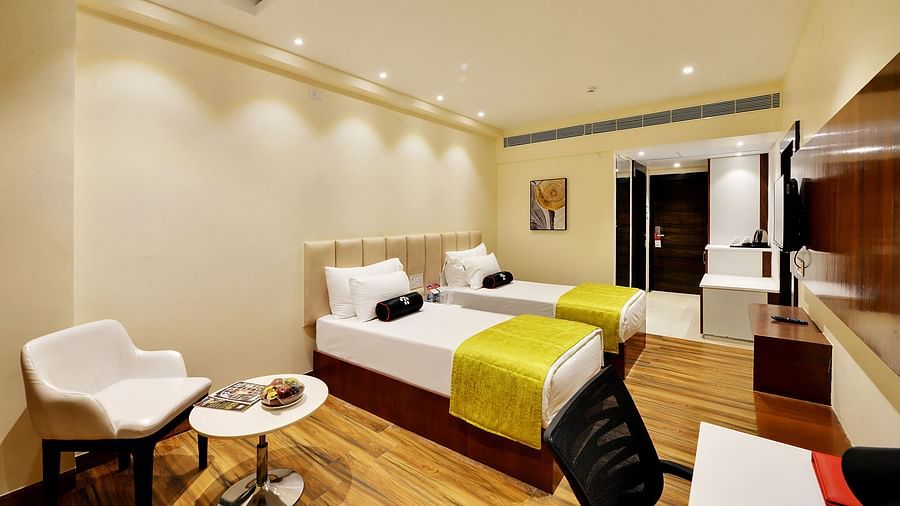 twin beds placed in the room, with a chair and an accompanying teat bale.
