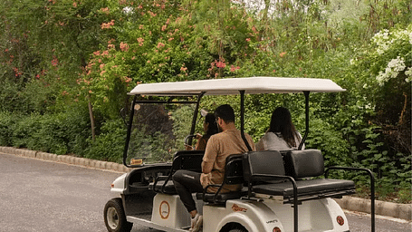 Rear view of a golf cart carrying two people on a road at Karma Chalets.