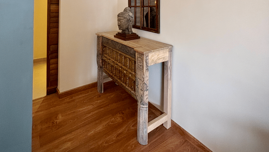 A corner of Vana Junior Suite at Surpura Bagh featuring an table where an antique piece of lord Bhudda is placed.