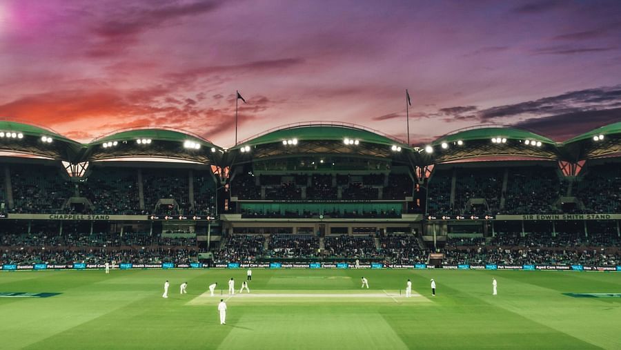 an image of a stadium with people playing cricket during dusk